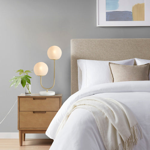 Two-light globe lamp glowing warmly on living room side table