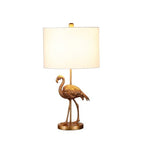 Gold flamingo decorative lamp glowing softly on bedroom nightstand