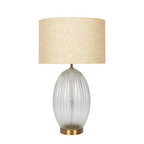 Ribbed glass base lamp glowing in bedroom nightstand setting
